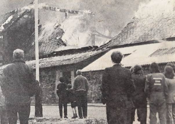 People look on as the roof of the factory collapses