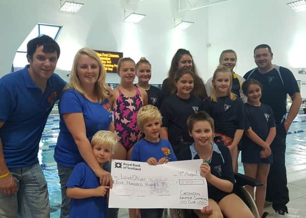 Katie, centre, with her friends from the Cardenden Swimming Club, handing over the cheque to the Gill family.