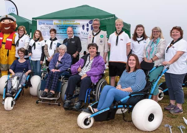 Scouts and leaders from the 8th Fife & 10th Cupar Explorer Scout units pictured with beach wheelchair users (from left) Maria Duncan (Glenrothes), Linda Simpson (St Andrews), Mona Ross (St Andrews), Kitty Walker (Lundin Links) and Amy Newton (Dairsie) plus (back, 1st left) Ask Andrew Ambassador Jackie Mackay,  RNLI mascot Stormy Stan,  (back, centre) Beach Wheelchair Committee member Jerry Beaulier and (back, 2nd right) Councillor Ann Verner.