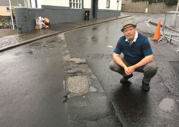 Cllr Johnny Tepp examining a section of damaged roadway in Fife.