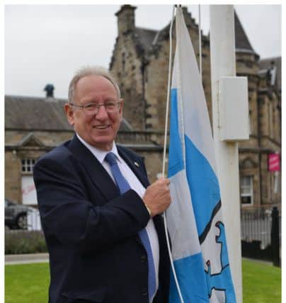 Robert Main hoists the flag at the town square