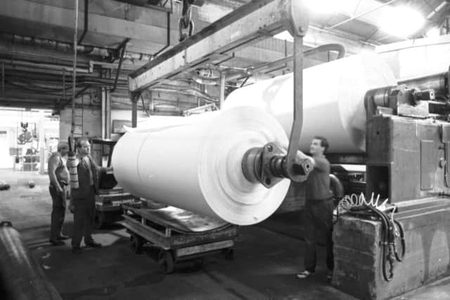 Men working with giant rolls of paper at  the Fife plant.
