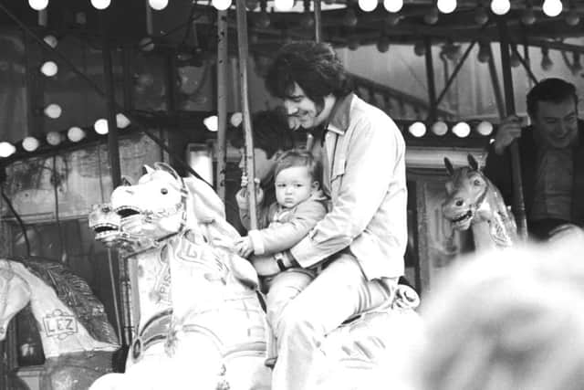 A man with championship sideburns on the carousel a the baby at the Links Market in. 1976