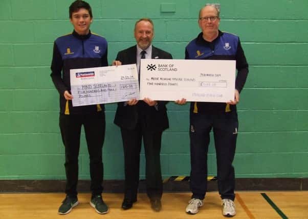 Falkland's Greg Chambers and Robbie Nellies hand over the cheque for just over £800 to Craig Stockton, chief executive, MND Scotland.