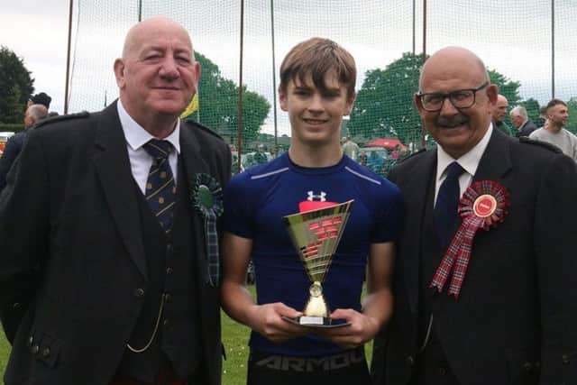 Ryan McMichen from Hawick receives the Duncan Family Trophy from Games chieftain Terry Braid with Chairman Jim Hutchison looking on.