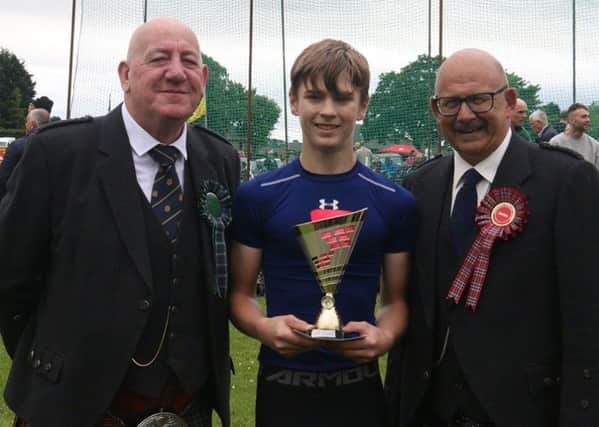 Ryan McMichen from Hawick receives the Duncan Family Trophy from Games chieftain Terry Braid with Chairman Jim Hutchison looking on.