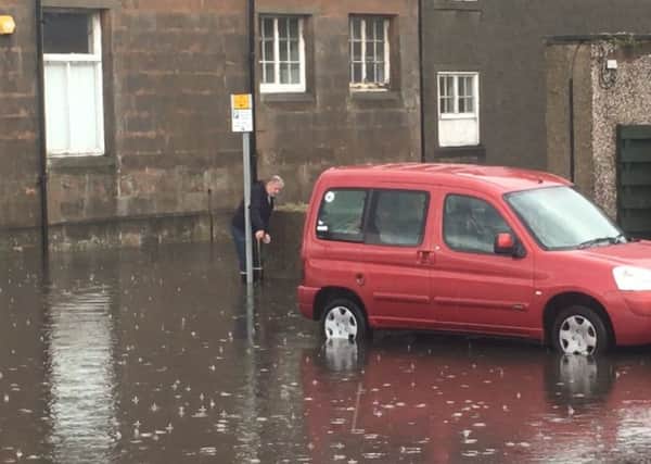 A man measures the depth of the floods at the Prom.