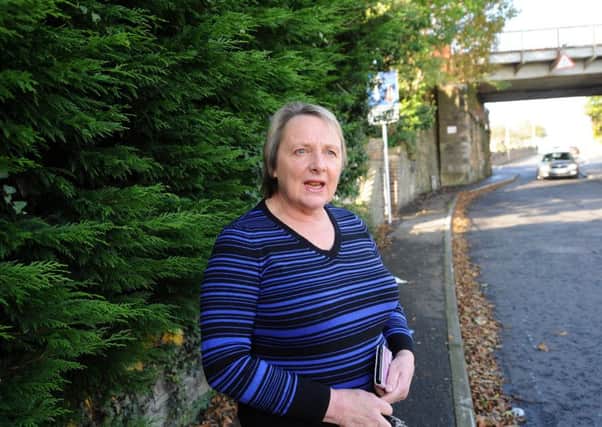 Lesley Weaver near the partially obscured sign at the railway bridge on Windmill Road.  Pic: Fife Photo Agency