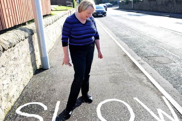 Lesley Weaver at the SLOW sign on the pavement near the railway bridge on Windmill Road.  Pic: Fife Photo Agency